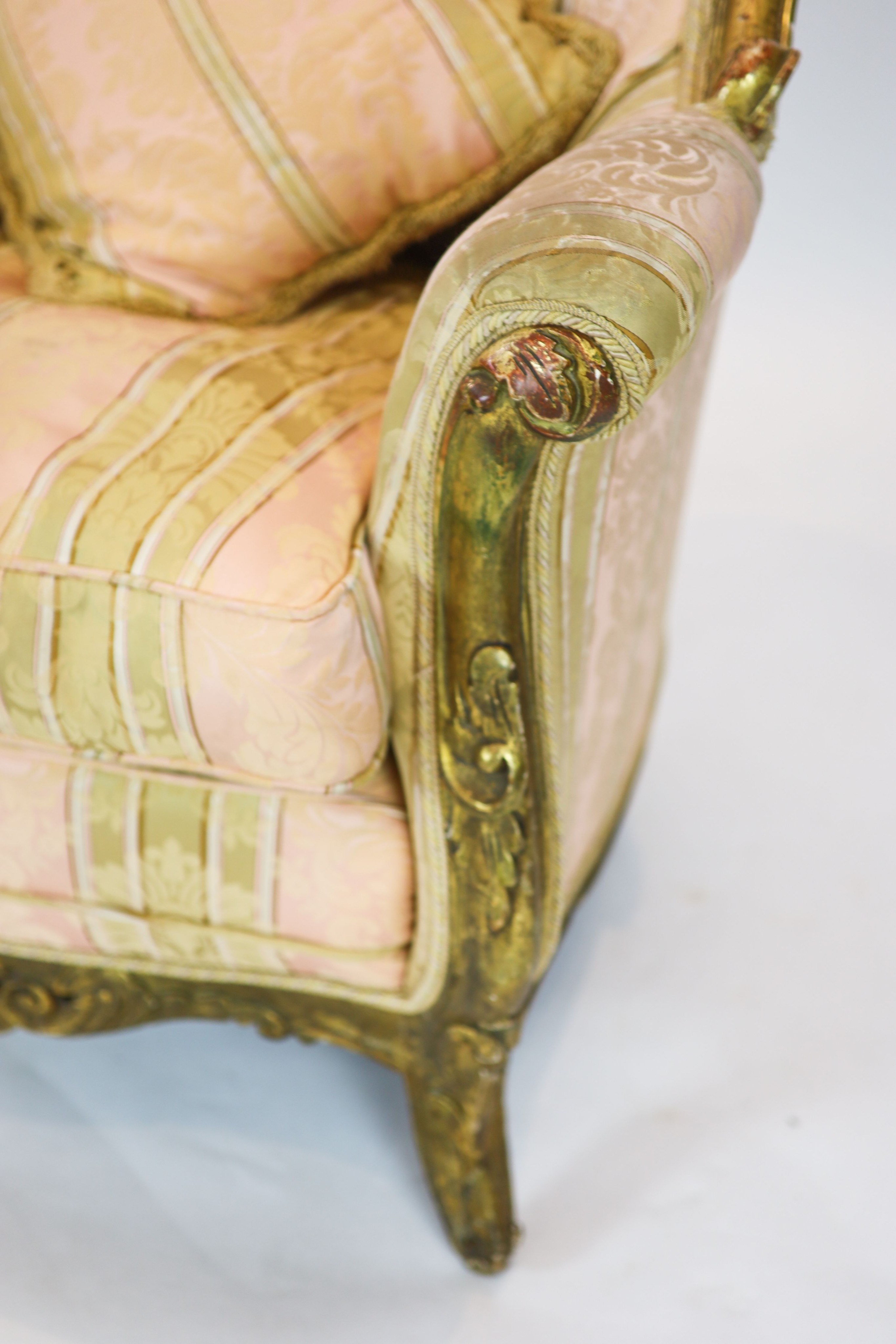 A Louis XV style carved gilt wood five piece suite, consisting of a three seater settee and four fauteuils, all with scroll carved backs and arms, on short cabriole legs